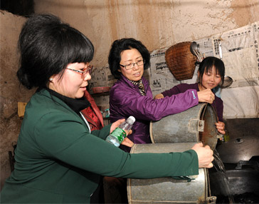 Qin Guoying, secretary-general of the China Women's Development Foundation under the All-China Women's Federation, pours water into a local villager's pot. [water cellar for mothers project office]